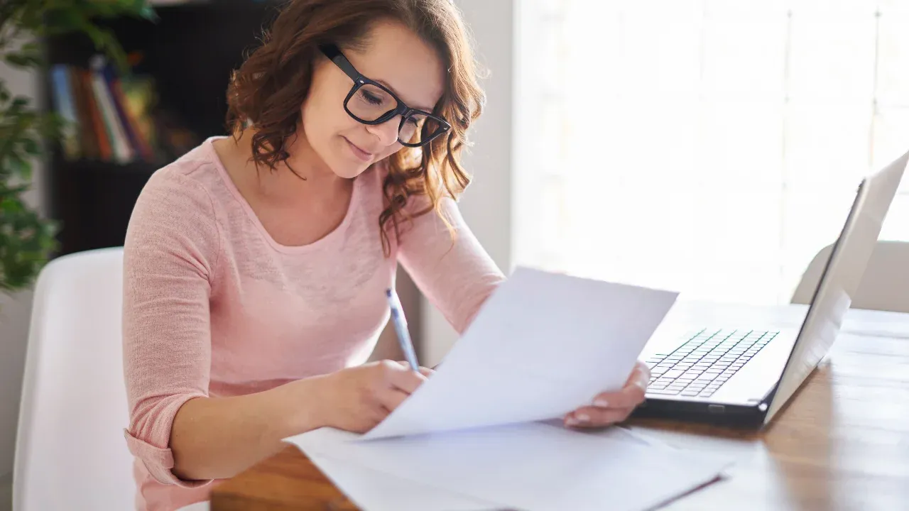 Woman sitting at desk reviewing a paper.