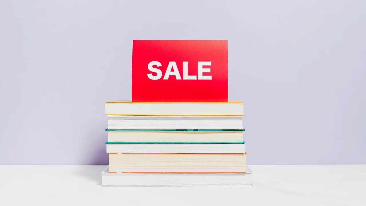 Stack of books with spines facing inward and sale sign on top.